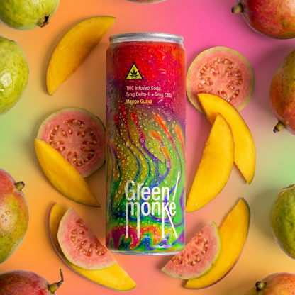 A colorful beverage can of Green Monke hemp THC-infused soda, upright in a styled flat lay surrounded by whole and sliced guava and mango fruits on a bright gradient background.